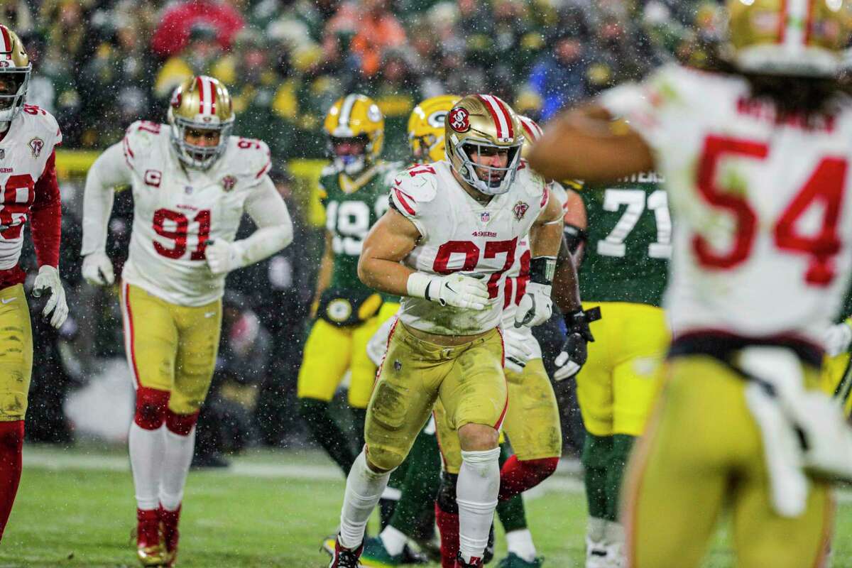 Snow falls as San Francisco 49ers defensive end Nick Bosa (97) runs on the fiel between plays as the San Francisco 49ers play the Green Bay Packers in the NFL Divisional Round playoff game at Lambeau Field in Green Bay, Wis., on Saturday, January 22, 2022.