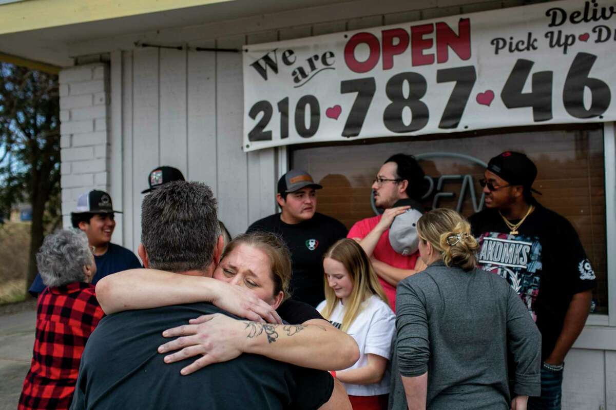 Dawn Pratt embraces Randy Sawers after selling out of food at Two Sawers BBQ in Floresville on Saturday, the restaurant’s last day in business.