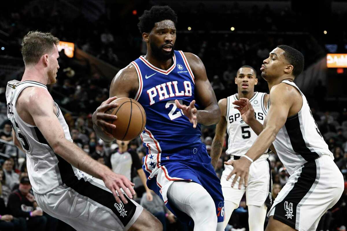 The 76ers’ Joel Embiid (21) tangles with the Spurs’ Jakob Poeltl, left, Keldon Johnson, right, and Dejounte Murray during the first half Sunday, Jan. 23, 2022, in San Antonio.