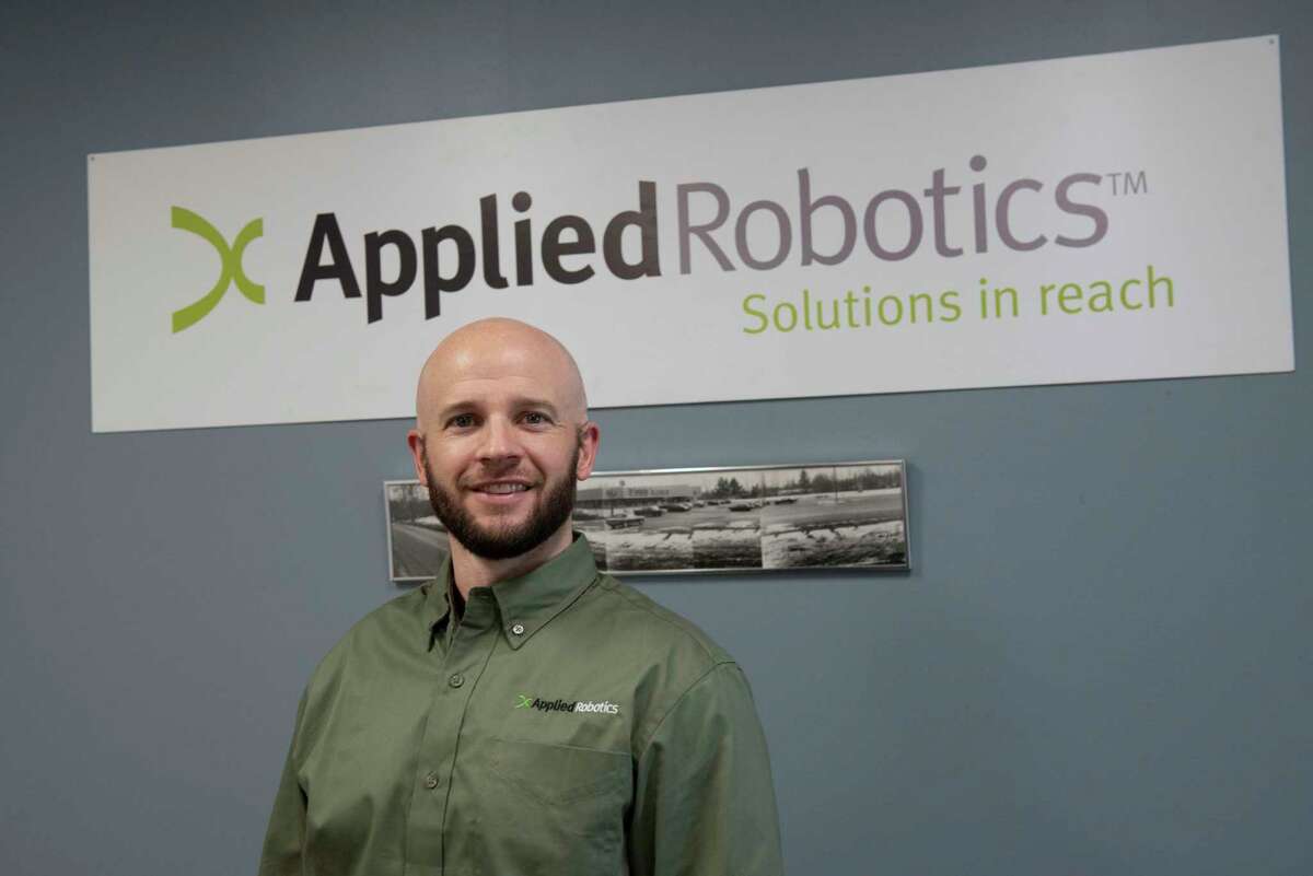 Applied Robotics COO Stefan Casey stands in front of the logo in the factory’s lobby on Friday, Jan. 21, 2022 in Glenville, N.Y.
