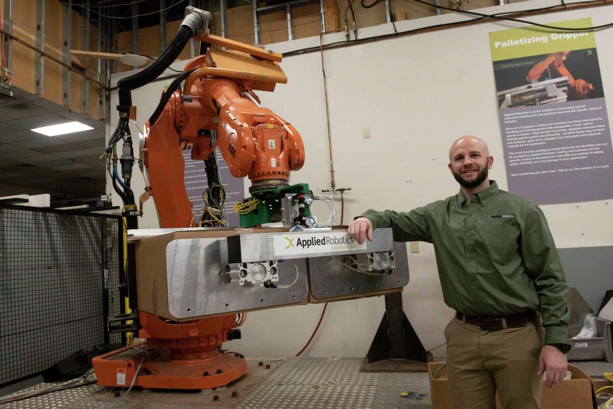 Applied Robotics COO Stefan Casey stands next to a palletizing gripper holding boxes at Applied Robotics on Friday, Jan. 21, 2022 in Glenville, N.Y. The company produces the end-of-arm device for this robotic tool.