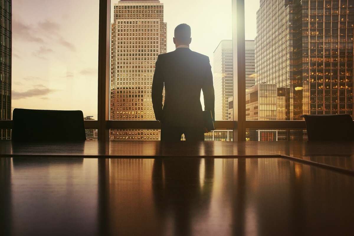 FILE — A businessman looks out at a financial district.