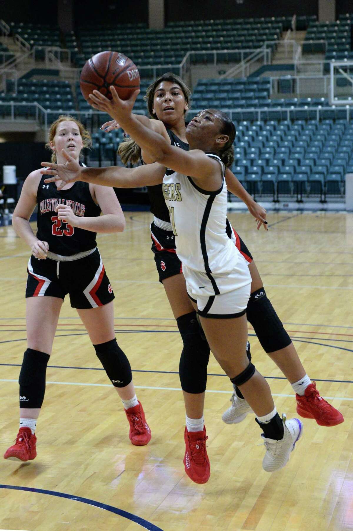 Kennedy Powell (11) of Conroe drives to the basket past Gabrielle Gipson (22) of Colleyville Heritage during the first half of a game between the Conroe Tigers and the Colleyville Heritage Panthers in the Katy ISD Basketball Classic on Friday, December 3, 2021 at the Leonard Merrill Center, Katy, TX.