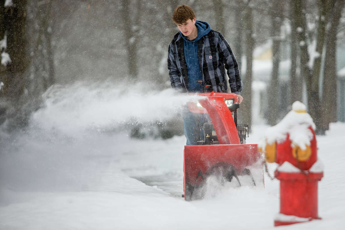 Josh Brawt uses a snowblower to clear a sidewalk Monday, Jan. 24, 2022 in Midland.