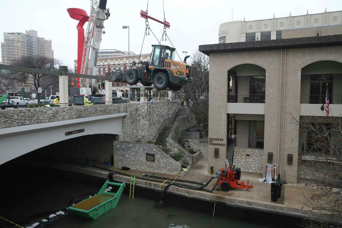 A CASE wheel loader, weighing over 12 tons, is hoisted to the San Antonio River bed by a crane Monday. The biennial draining and cleaning the river started on Sunday. The crane is also used to hoist a container with debris out of the river. Alamo Street between Commerce and Market streets is closed due to the work.