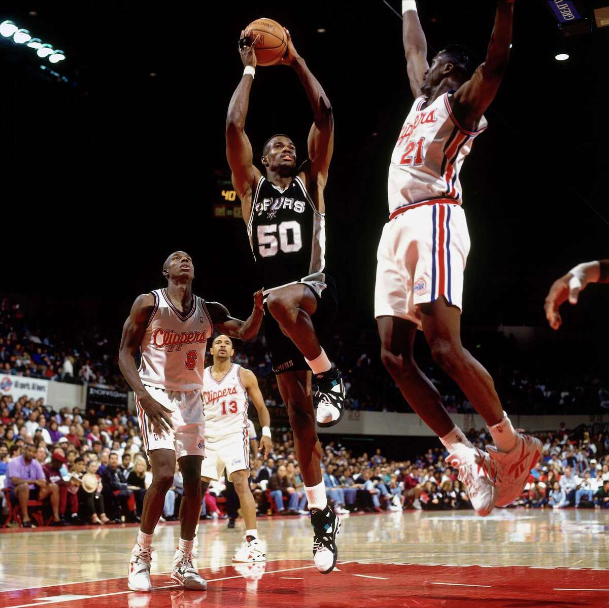 David Robinson (50) of the Spurs shoots between Dominique Wilkins (21) and Charles Outlaw (6) of the Clippers on April 24, 1994 at the Los Angeles Memorial Sports Arena. David Robinson finished the game with 71 points to clinch the 1994 league scoring title.