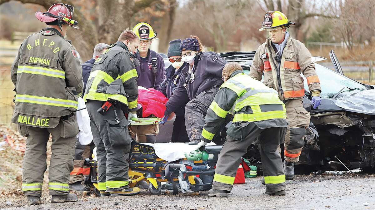 John Badman|The Telegraph Alton Memorial Ambulance paramedics and firefighters from Fosterburg and Shipman help prepare a subject for transport who was reportedly ejected from an Ford SUV Monday just before 11 a.m. near the 4500 block of Woodburn Road in rural Brighton in Macoupin County. An ARCH Air Medical Services Inc. helicopter landed in a nearby field to airlift the person to a St. Louis trauma center. 