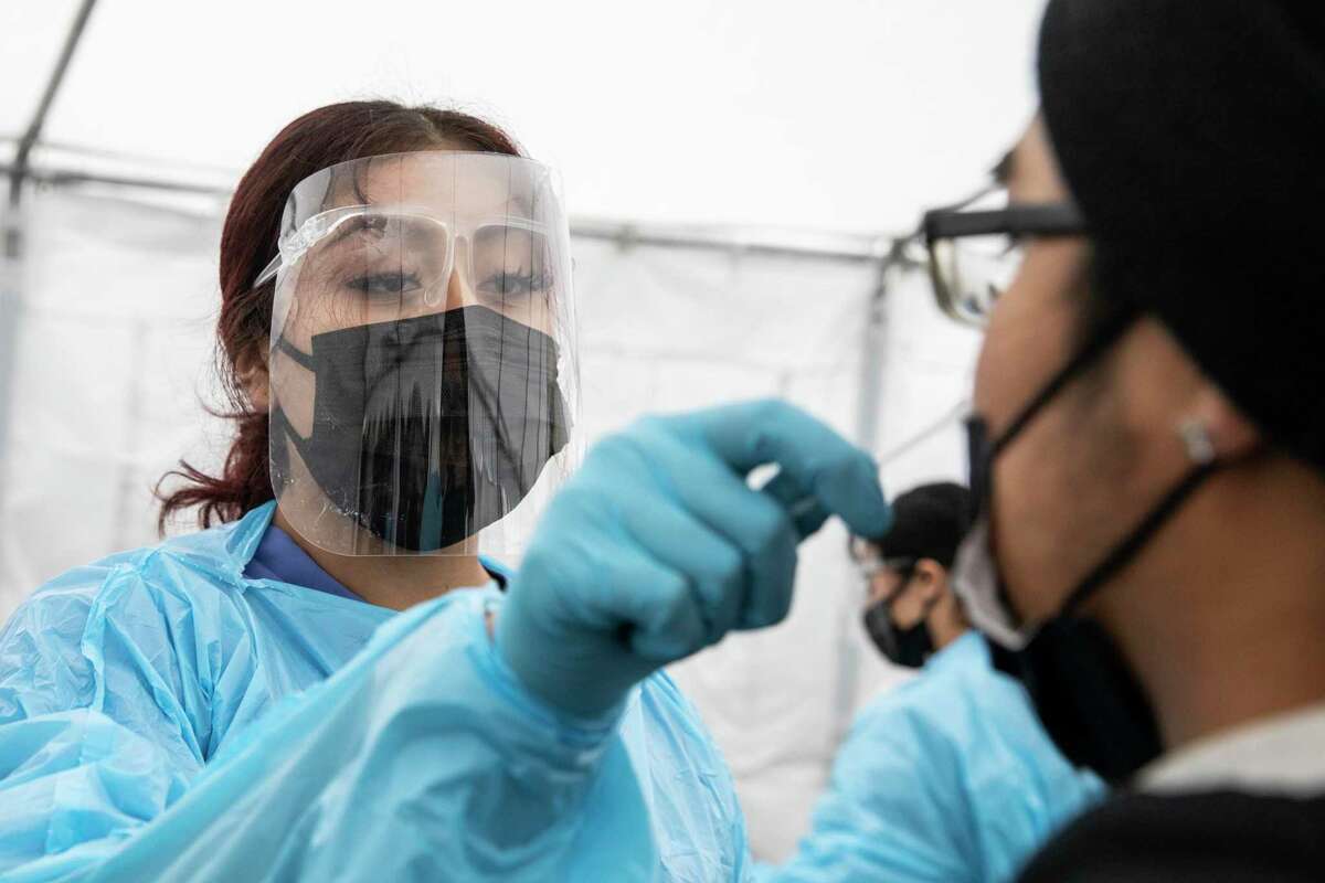Medical Assistant Cindy Mon (left) administers a coronavirus test to Victor Torres, who delivers food to people under quarantine, at Unidos En Salud in the Mission District of San Francisco.