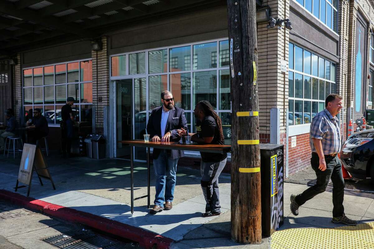 Customers chat outside Blue Bottle Coffee in Oakland. The warehouse will transform into a brewery and restaurant by Cellarmaker.