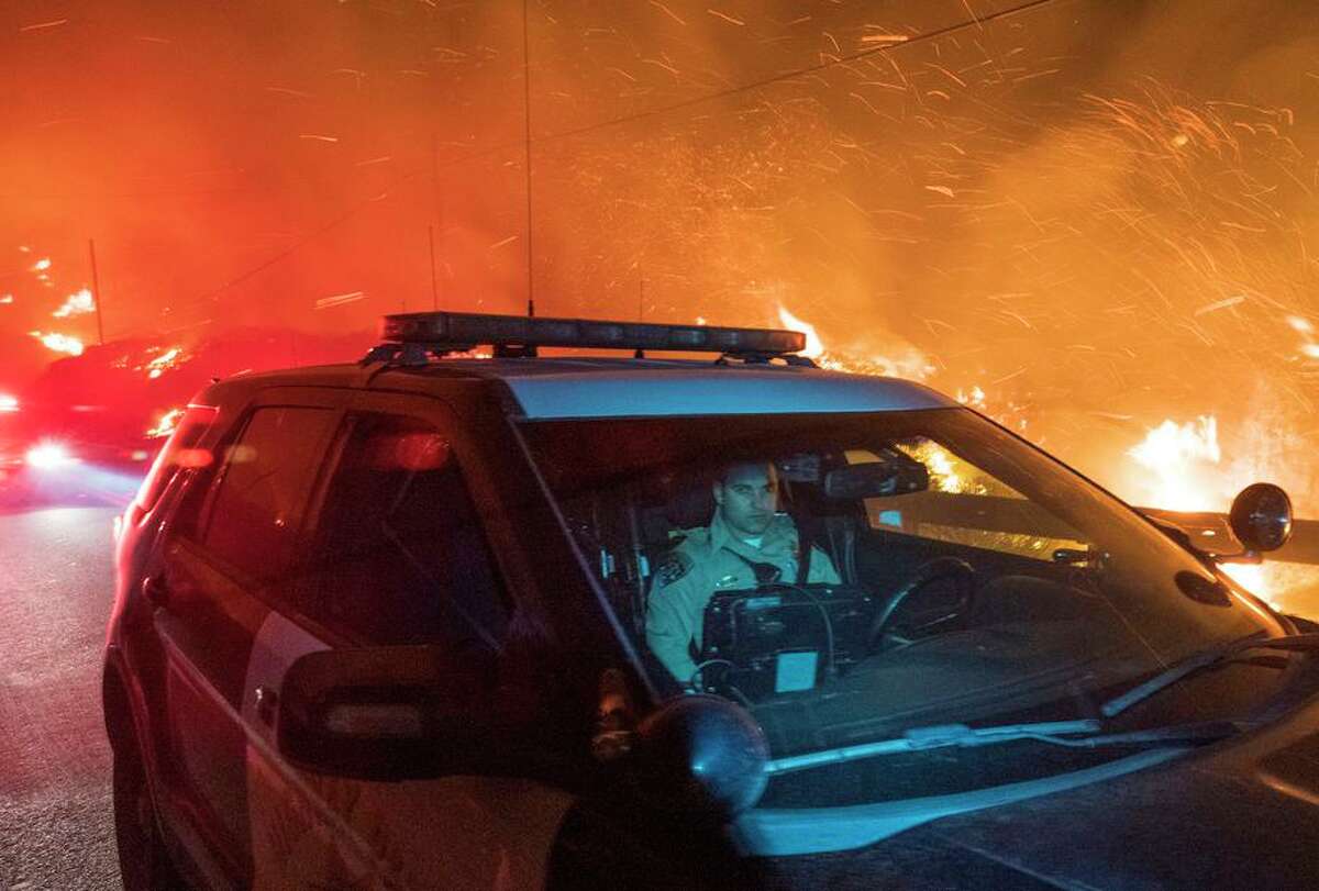 A California Highway Patrol officer drives south on Highway 1 as the Colorado Fire burns in Big Sur late Friday.