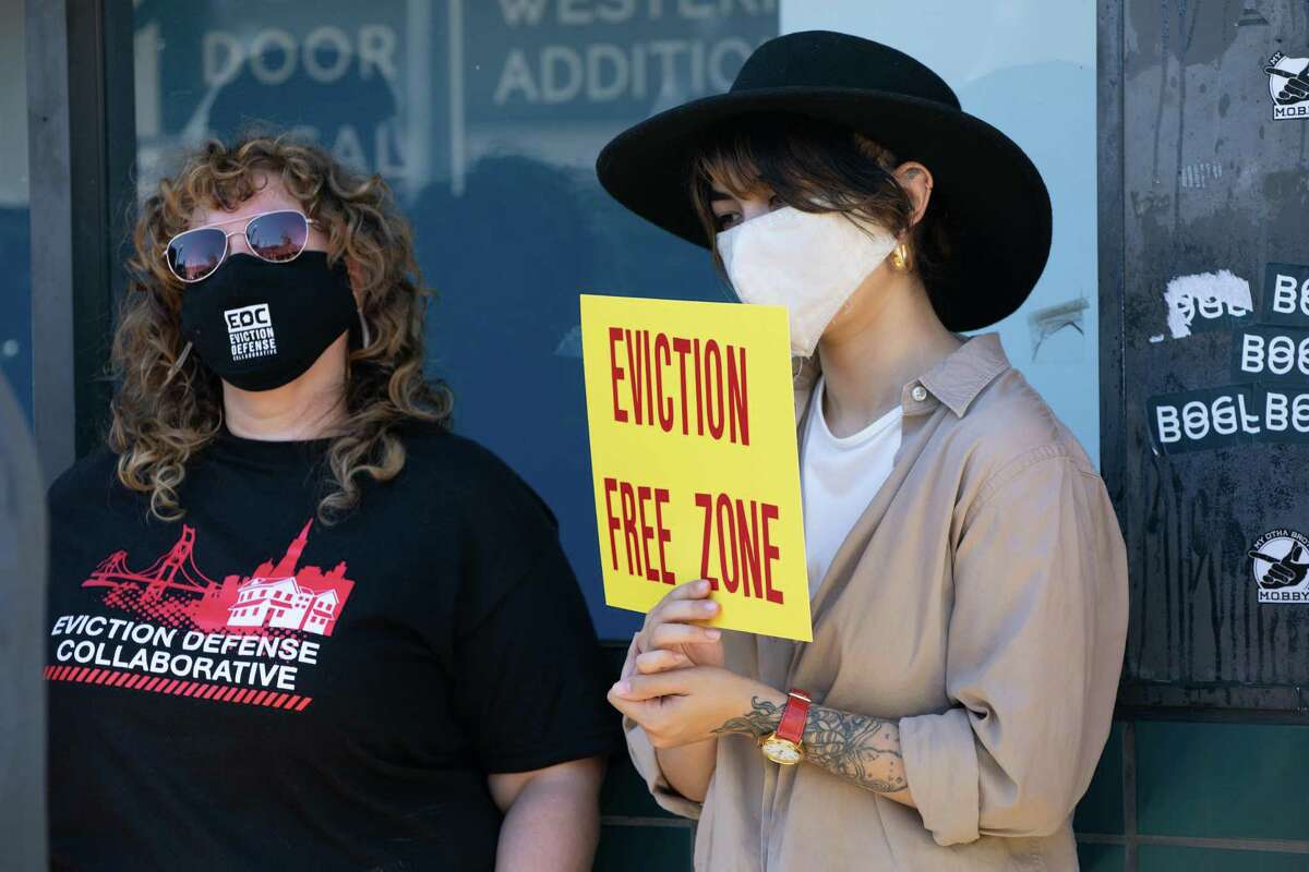 Attendees hold signs at a an event in the Fillmore protesting evictions on Oct. 1, 2021, in San Francisco.