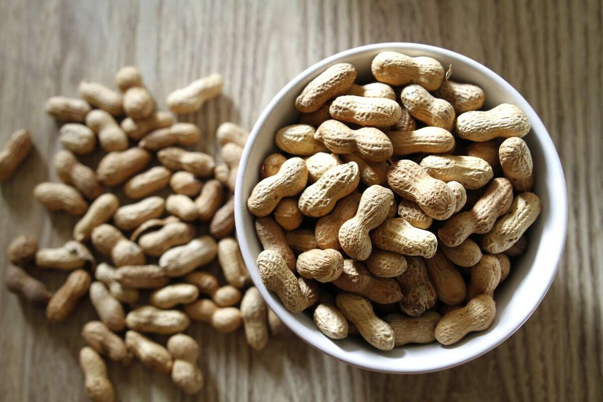 Bowl of peanuts on wooden table. 