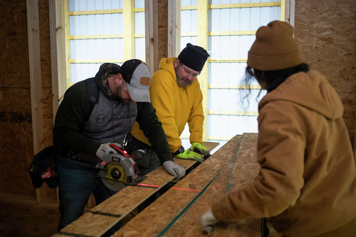 From left, Cameron Lavely, Dave Abbott and Alesha Saylor work on a home being built for a family in need Monday, Jan. 24, 2022, through a partnership between Habitat for Humanity and Greater Midland Construction Academy.