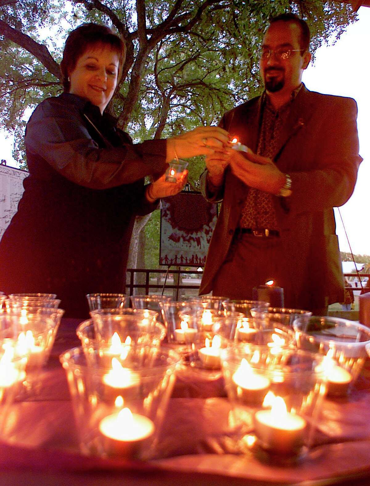 In this Oct. 21, 1999, file photo, Comal County Women’s Center counselor Ginger Gray, left, and executive director Danny Perez light candles at Landa Park in New Braunfels before a candlelight vigil honoring victims and survivors of domestic violence.