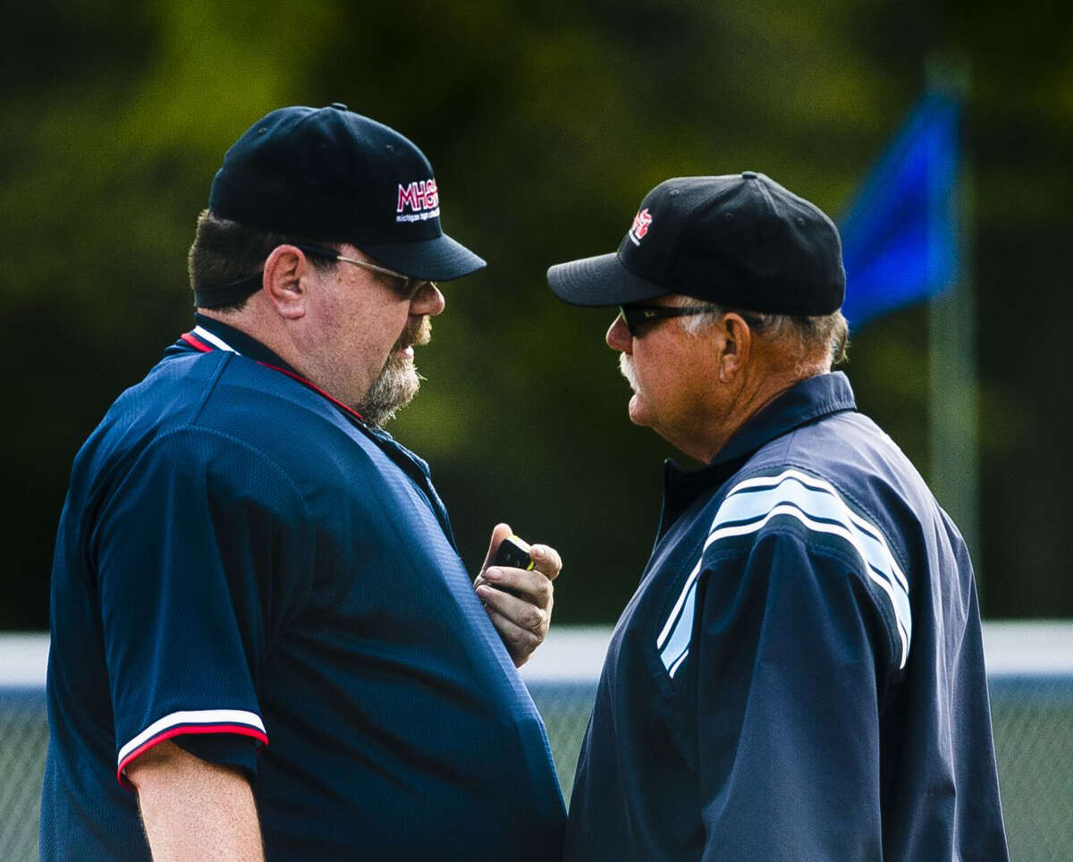 Midland's Jason Harper (left) confers with fellow umpire Rick Havercroft during a May 22, 2018 softball game between Meridian and Beaverton.