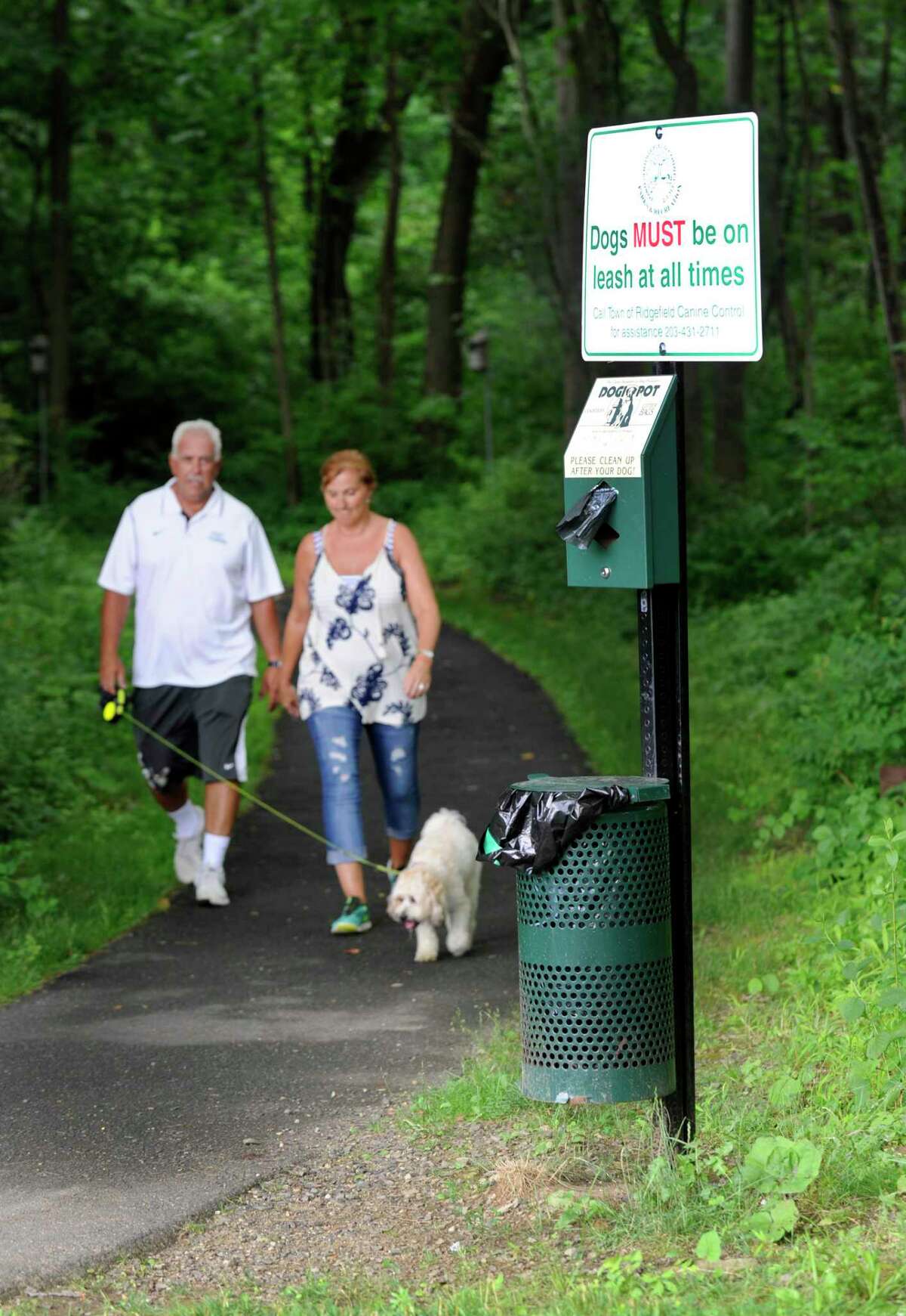 Residents Robert and Julia Howard walk their dog past a receptacle at the Ridgefield Recreational Center. Taken July 11, 2017, in Ridgefield, Conn.