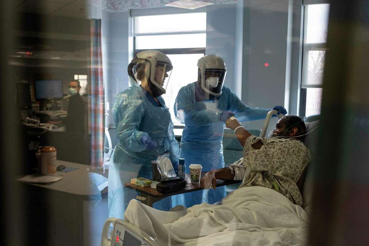 Director of Critical Care Kanak Patel, center, and Andrea Donohue, PA, left, check on a covid ICU patient at Doctors Hospital in Lanham, Md. on Jan. 14.