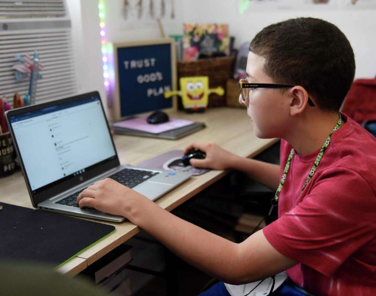 Isaac Lopez, 11, uses his laptop for remote learning with his mother, Jodi Clark-Lopez, at their home in Stamford, Conn. Monday, Aug. 16, 2021.