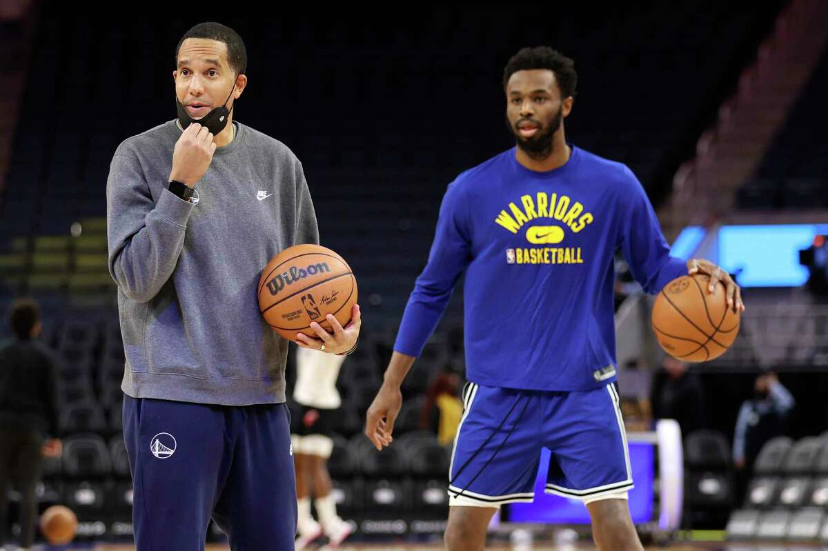 Golden State Warriors assistant coach and director of player development Jama Mahlalela, left, stands next to Golden State Warriors forward Andrew Wiggins during practice before an NBA basketball game against the Detroit Pistons in San Francisco, Tuesday, Jan. 18, 2022. Coach Steve Kerr and his assistants met during the summer along with Stephen Curry and Draymond Green to review how they might practice more efficiently and with greater focus, and the resulting “Golden Hour” has meant so much to Golden State’s success so far.(AP Photo/Jed Jacobsohn)