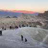 Some sunrise spectators walk out into the badlands near Death Valley National Park's Zabriskie Point.