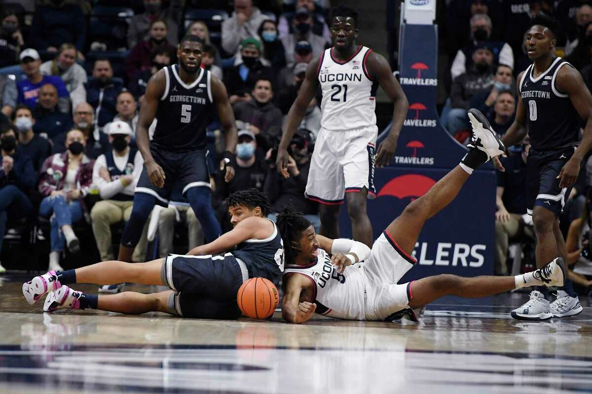 Georgetown’s Collin Holloway, left, and UConn’s Isaiah Whaley, right, dive for a loose ball in the first half of an NCAA college basketball game, Tuesday, Jan. 25, 2022, in Storrs, Conn.