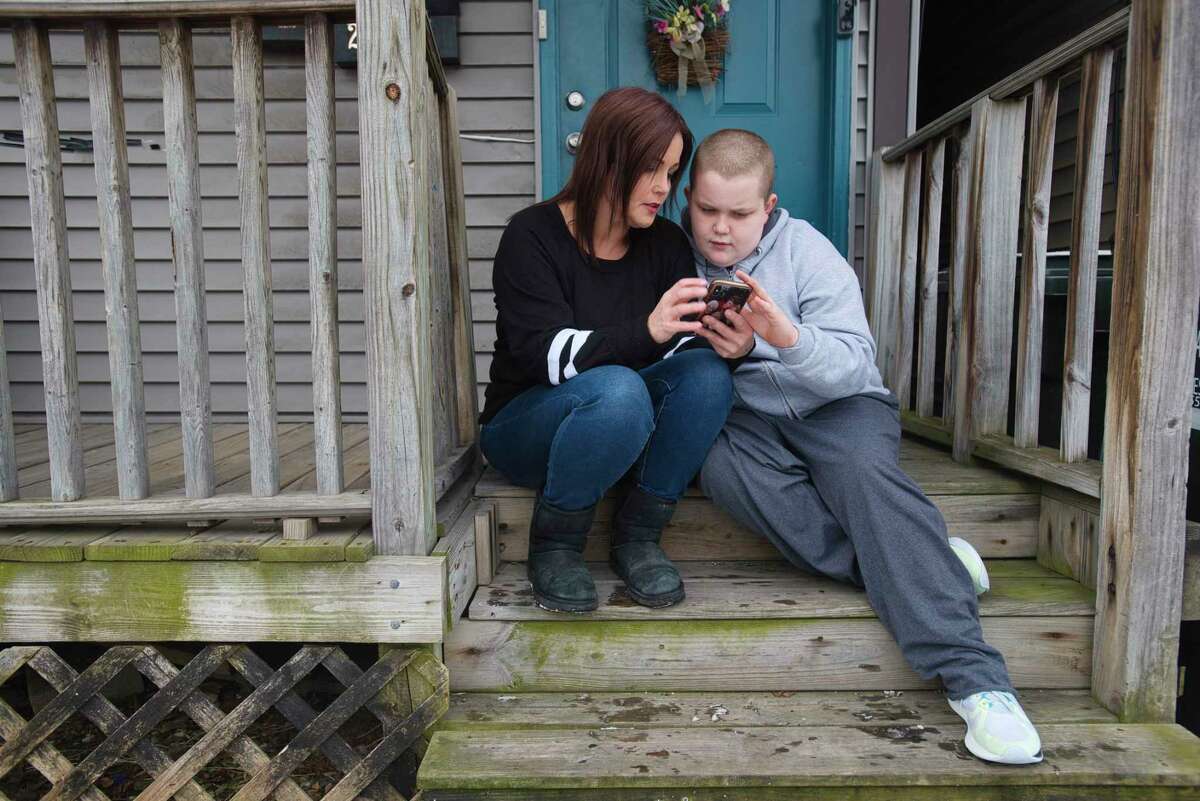 Amanda Nacco, sits on the porch with her son, Dylan Goering, 12, on Tuesday, Jan. 25, 2022, in Green Island, N.Y. Dylan and his schoolmates have not had access to full-time, in-person instruction since the pandemic began in March 2020.
