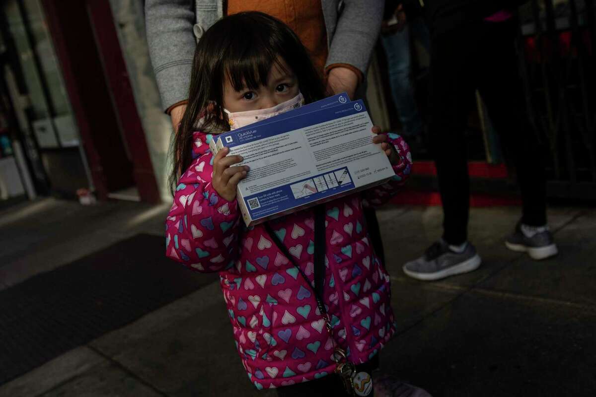 唐人街社区发展中心外，一名儿童手持冠状病毒检测试剂盒。