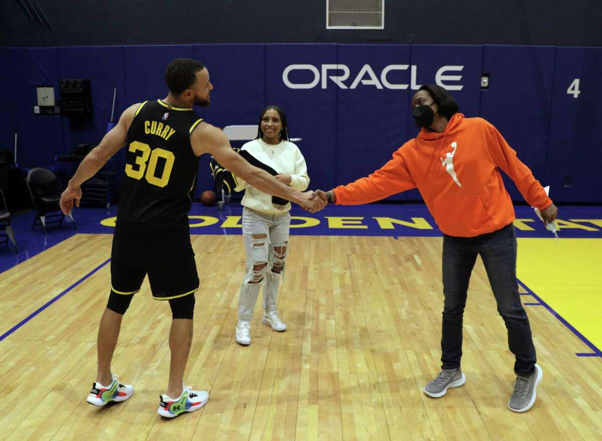 Jayda Curry watches as her coach Charmin Smith shakes hands with Stephen Curry, whose number Jayda wears while playing at Cal after the Golden State Warriors played Dallas Mavericks at Chase Center in San Francisco, Calif., on Tuesday, January 25, 2022.