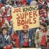 Fans in gold satin San Francisco 49ers jackets stand alongside someone holding a sign referencing Joe Montana during a 1990 NFL game against the Los Angeles Rams at Candlestick Park.