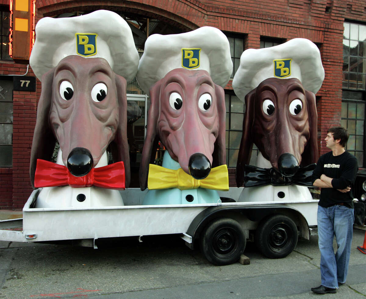 Nick Jumonville of New Orleans looks over a trio of Doggie Diner heads parked outside an art gallery and wine bar for an exhibit opening in San Francisco, Wednesday, Jan. 12, 2005. The characters were once the figureheads atop the two dozen Doggie Diner hot dog stands that existed from 1949 to 1986 in the San Francisco Bay area.