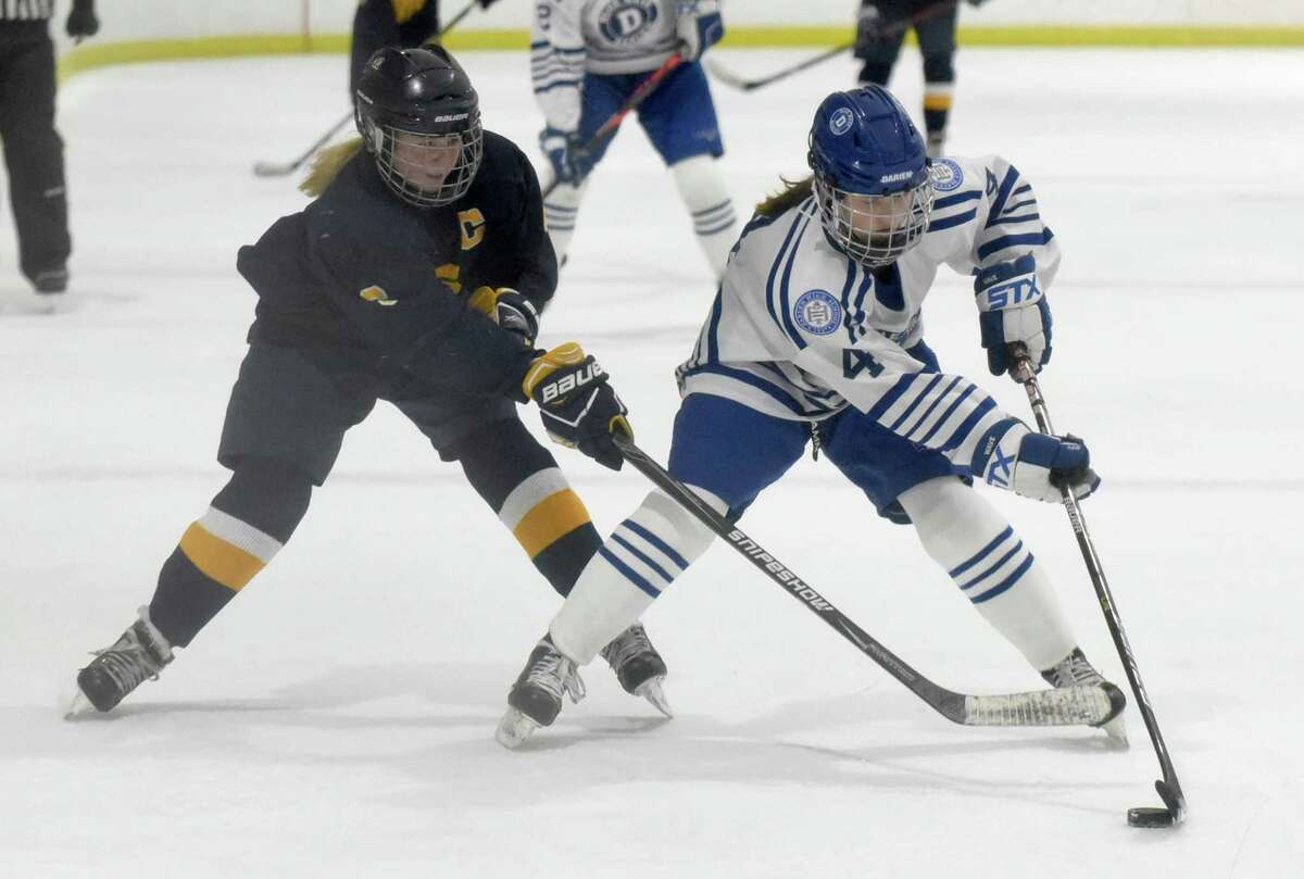 Darien's Keira Austen (4) and Simsbury's Mackenzie Chapman (6) battle for the puck during a girls ice hockey game at the Darien Ice House on Wednesday, Jan. 26, 2022.