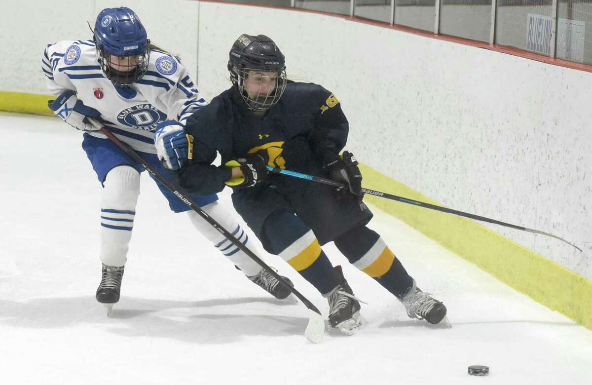 Simsbury’s Lucy Humphreys (16) angles for the puck while Darien’s Sarah Kellogg pursues during a girls ice hockey game at the Darien Ice House on Wednesday.