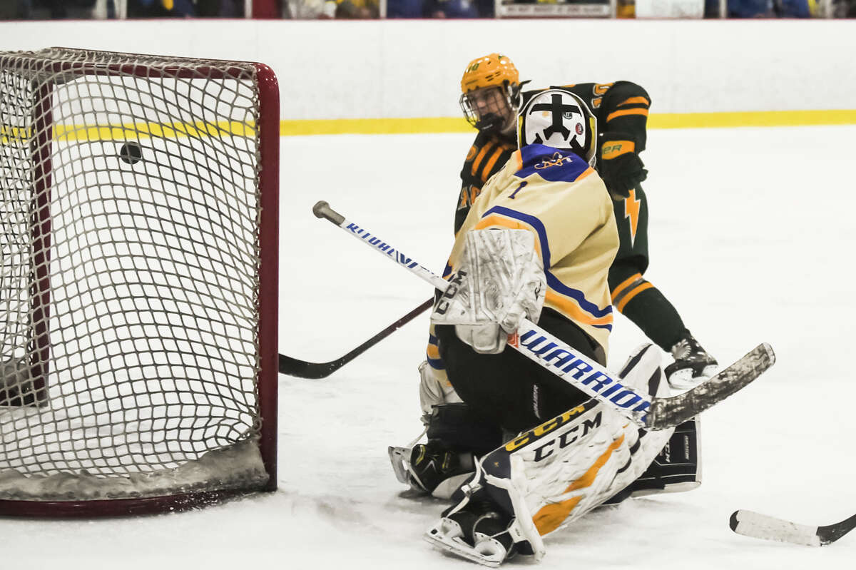 Dow's Caden Chritz flips the puck past Midland's goalie during their game Wednesday, Jan. 26, 2022 at Midland Civic Arena.