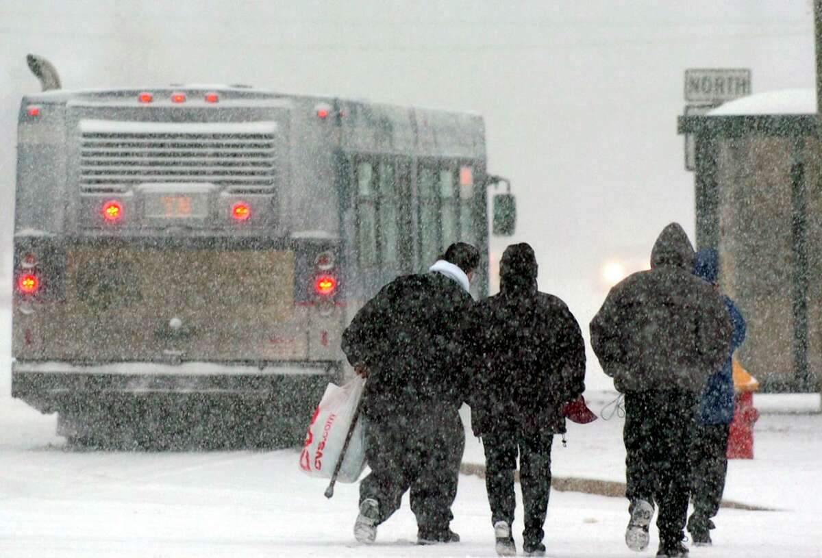 A bus makes a stop for passengers as they cross a snow-covered road amid a winter storm Sunday, Dec. 14, 2003, in Wethersfield, Conn. (AP Photo/Douglas Healey)