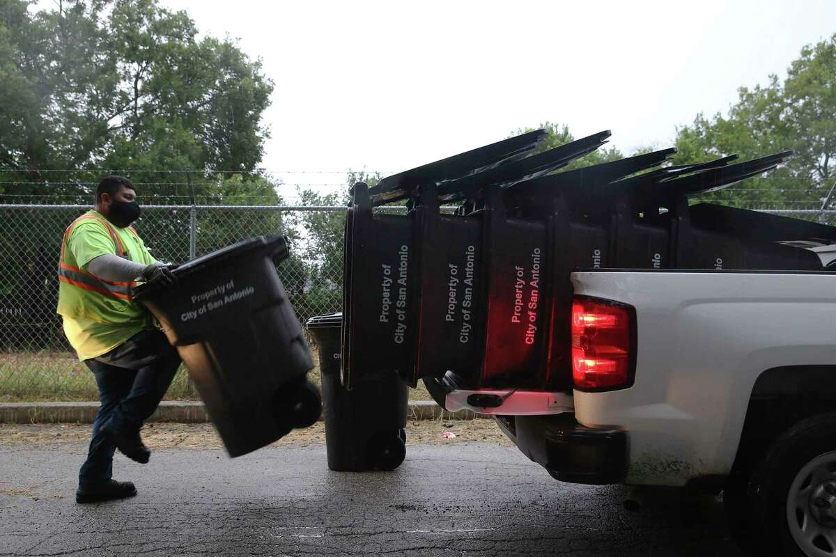 FILE — City of San Antonio Solid Waste Management employees pick up trash cans in the Camelot II subdivision of Bexar County, Monday, Aug. 2. After most City Council members said last year they want to see premium, or hazard, pay for city employees, City Manager Eric Walsh suggested a new way to support workers. Staff proposed $10 million for employee compensation and retention.