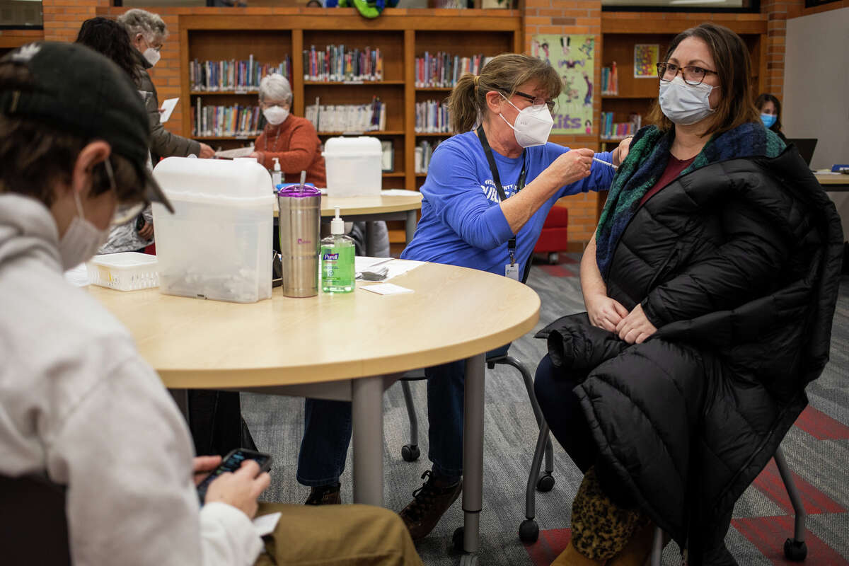 Lindsey Pence, right, receives a booster dose of the COVID-19 vaccine during a vaccine clinic Wednesday, Jan. 26, 2022 at Jefferson Middle School in Midland.