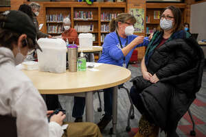 Lindsey Pence, right, receives a booster dose of the COVID-19 vaccine during a vaccine clinic Wednesday, Jan. 26, 2022 at Jefferson Middle School in Midland.