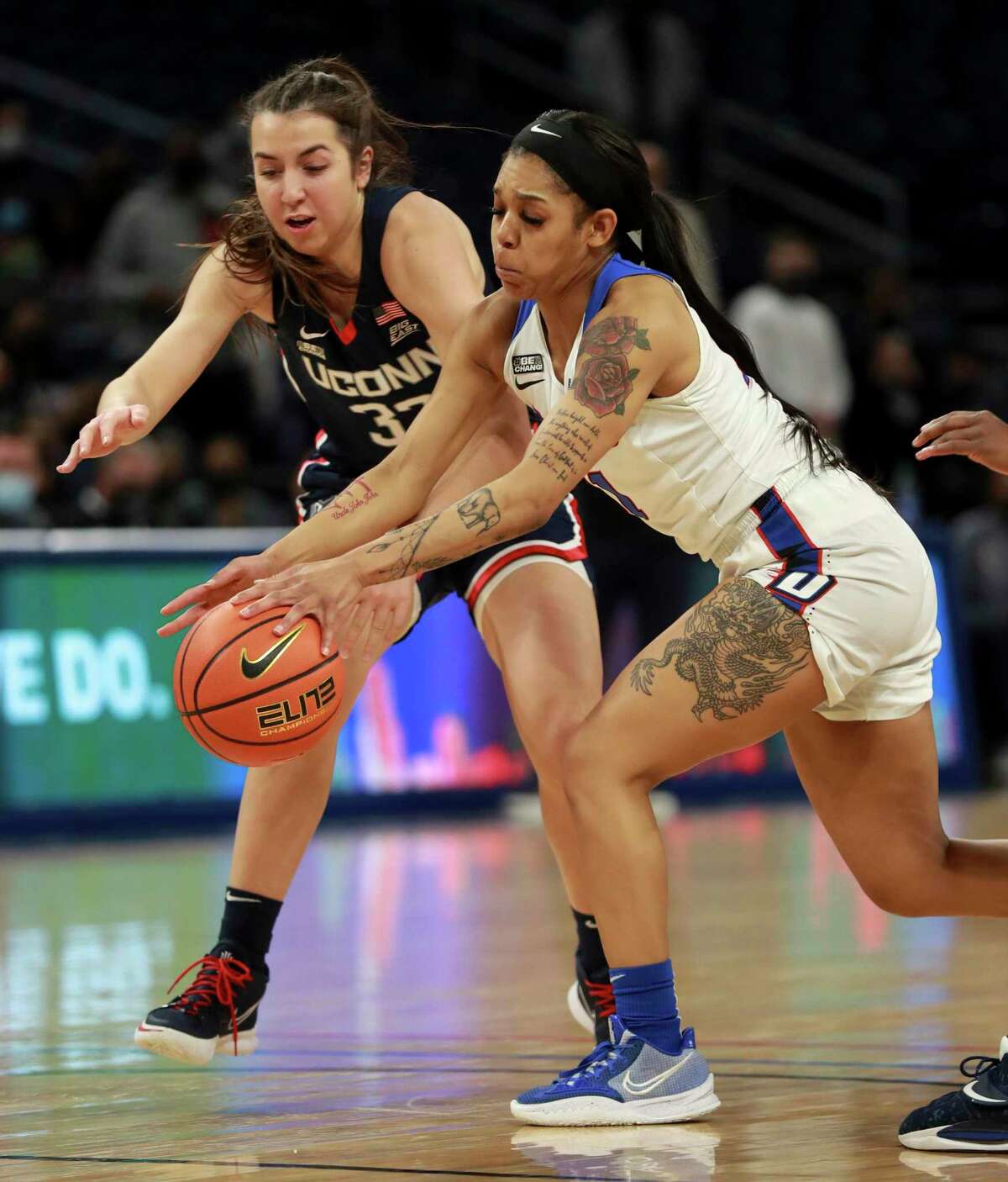 Connecticut guard Caroline Ducharme (33) and DePaul guard Sonya Morris reach for a loose ball in the first half of an NCAA college basketball game at Wintrust Arena in Chicago on Wednesday, Jan. 26, 2022. (Chris Sweda/Chicago Tribune via AP)