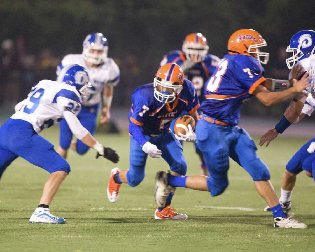 Danbury's Anthony Nejame (7) picks up a first down after catching a pass from quarterback Nick Hamed. Teammate William Jack provides a block while Darien's Cody Dizeo (29) moves in to make the tackle during an FCIAC game Friday, Sept. 24, 2010, at Danbury High School.