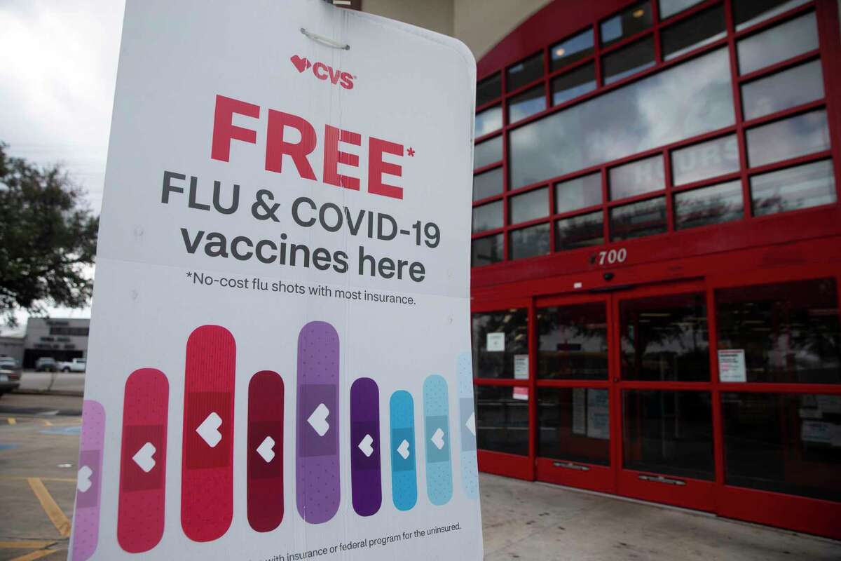 A CVS sign says the pharmacy provides free flu and COVID-19 vaccines Wednesday, Jan. 19, 2022, in Houston.
