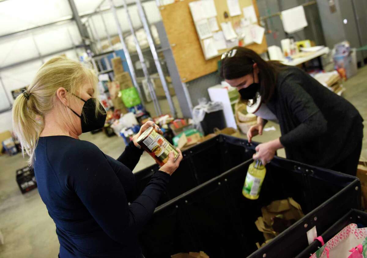 Volunteers Martha Spector, left, and Lauren Wilson check expiration dates of donated items at Neighbor to Neighbor food pantry's temporary location at 1 Horseneck Lane in Greenwich, Conn. Thursday, Jan. 27, 2022. Construction of the new facility at Christ Church has been delayed due to supply chain issues.