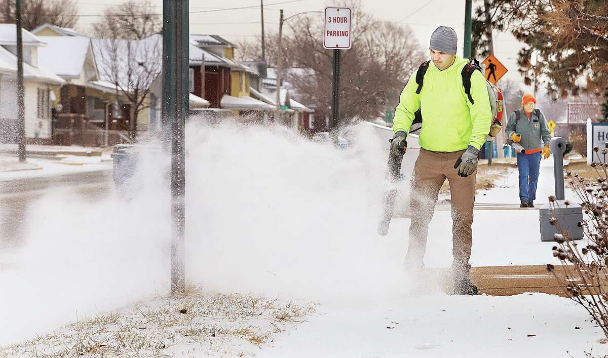 John Badman|The Telegraph After a dusting of snow across the area workers were busy Thursday morning blowing the snow off the sidewalk in front of the Wood River Library on Ferguson Avenue. The powdery snow didn't amount to much and did not close area schools.