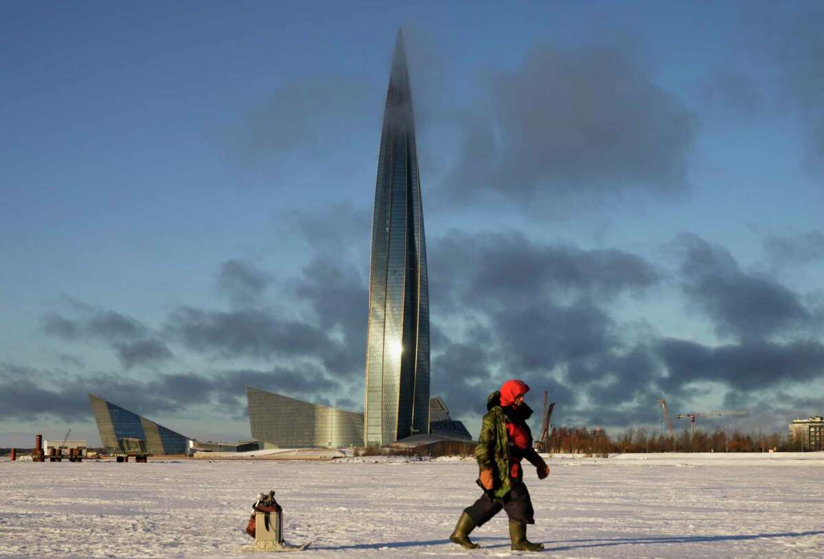A fisherman walks on the ice of Finnish Gulf past the business tower Lakhta Centre, the headquarters of Russian gas monopoly Gazprom in St. Petersburg, Russia, Thursday, Jan. 13, 2022.