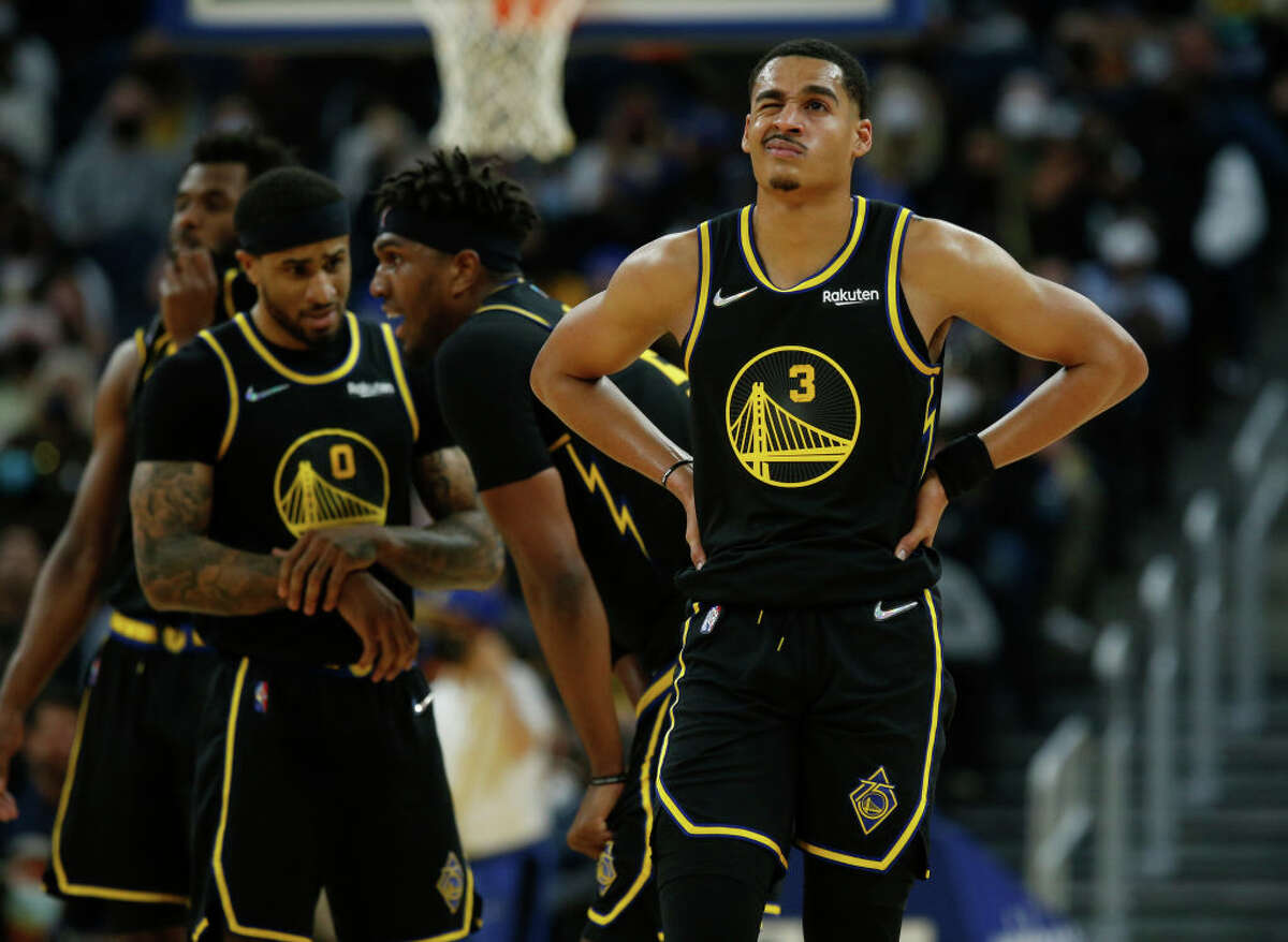 Golden State Warriors' Jordan Poole grimaces after being knocked to the court in the third quarter of an NBA game against the Dallas Mavericks at the Chase Center in San Francisco on Tuesday, Jan. 25, 2022.