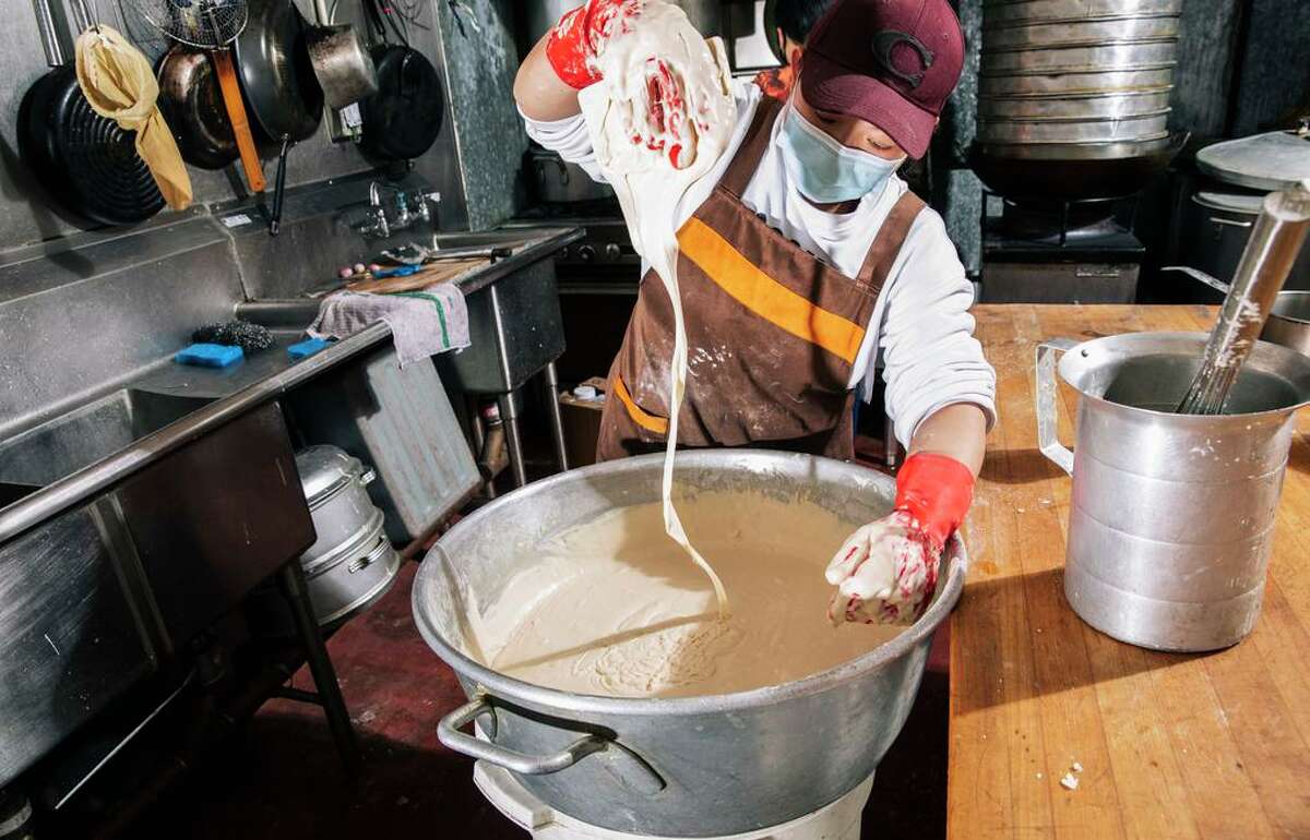 Hanna Zhang, owner of iCafe in Chinatown, checks the mixture’s consistency while making nian gao, or sweet rice cake, in preparation for the upcoming Lunar New Year.