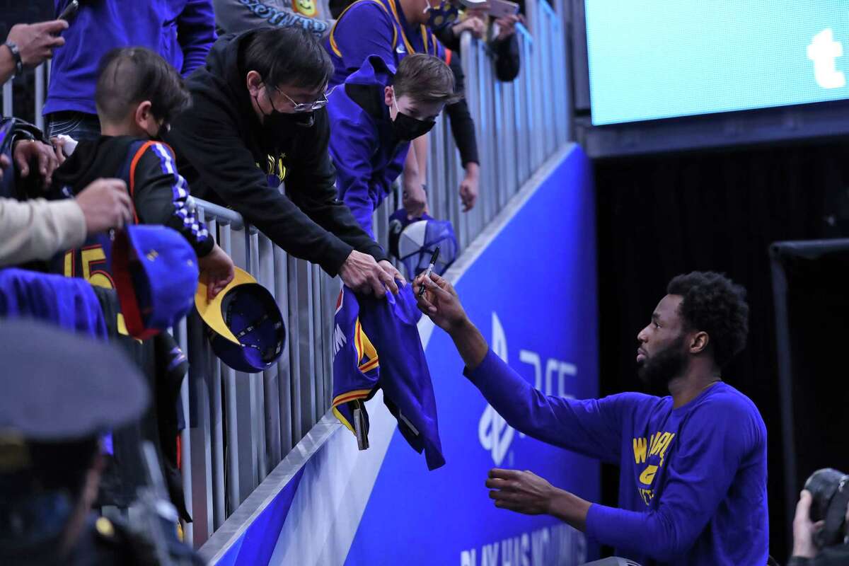 Golden State Warriors' Andrew Wiggins signs an autograph before Warriors play Minnesota Timberwolves in NBA game at Chase Center in San Francisco, Calif., on Thursday, January 27, 2022.