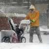 A man uses a snow blower to clear sidewalks along Main St. in Bridgeport, Conn. Feb. 1, 2021. The first major storm of 2022 is expected this weekend, with more than a foot of snow expected in parts of the state.