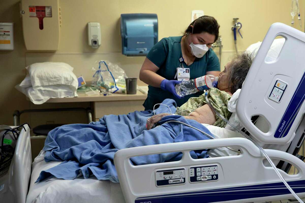 Jackie Cerros, a registered nurse at Texas Vista Medical Center, helps Maria Cruz drink water. Cruz is in the hospital’s intensive care unit, recovering from COVID-19.