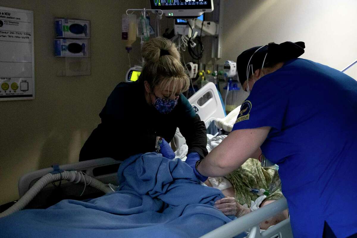 Tracy Olila (left), a registered nurse at Texas Vista Medical Center in San Antonio, tends to a patient in the intensive care unit while nursing student Ally Carman assists her.