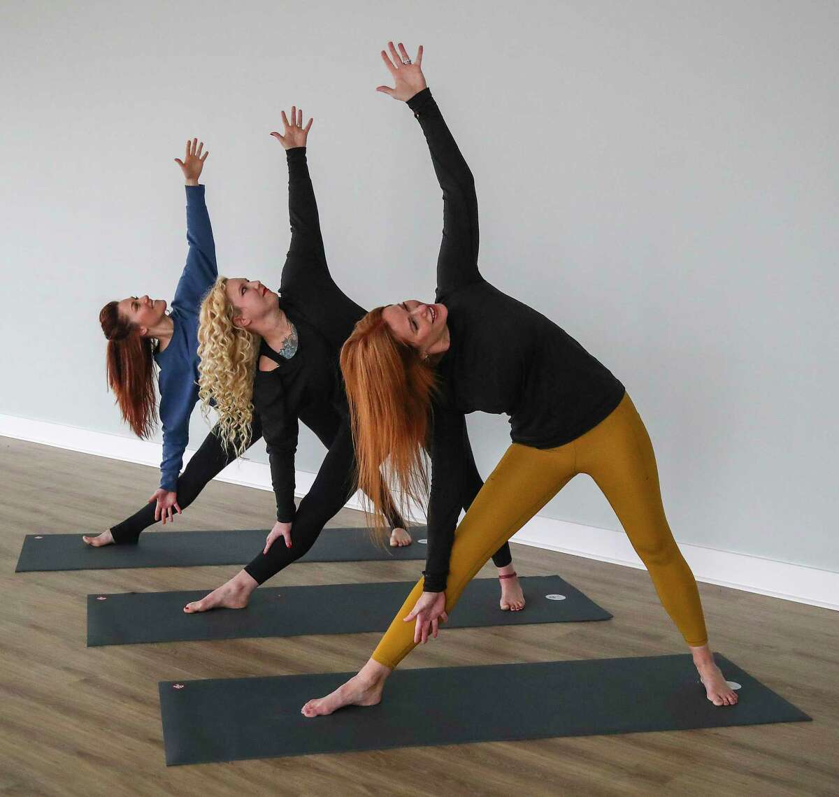 Amanda Hale, owner of Yoga Tres, forground, demonstrates a Triange pose with Heather Heft, center and Stacie Zollars, far left.